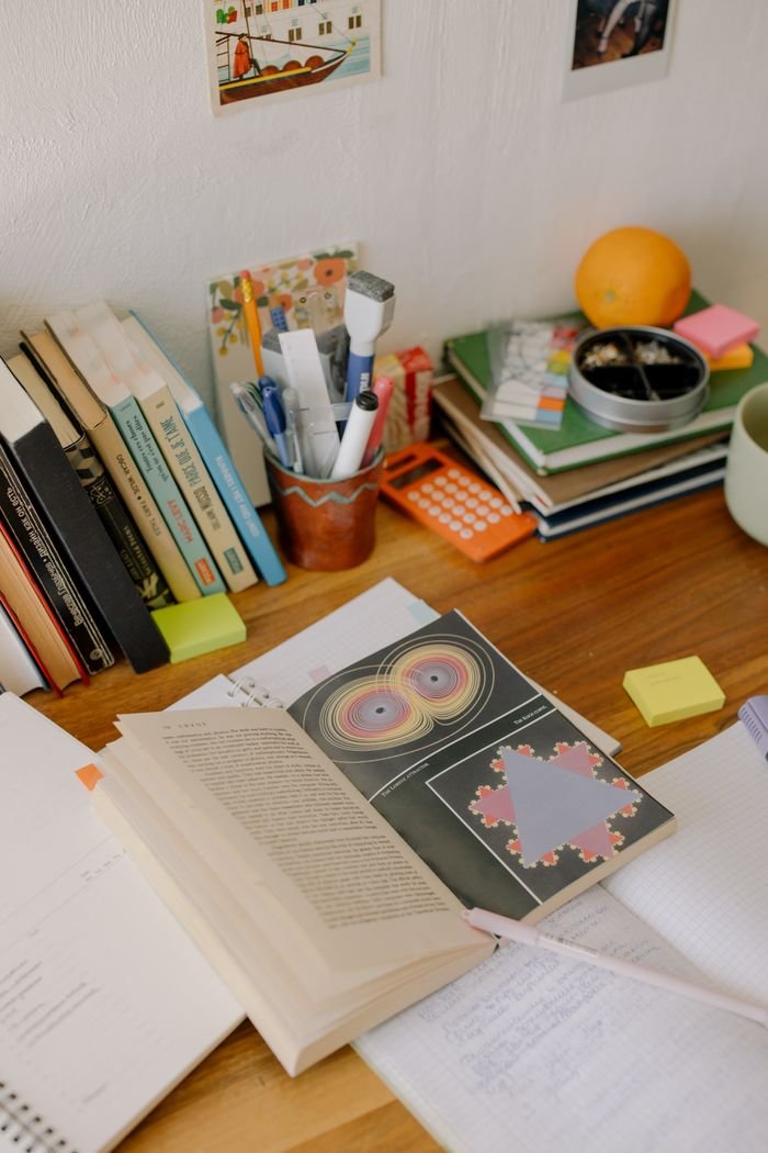 A study desk filled with open books, notebooks, and colorful stationery for academic work.