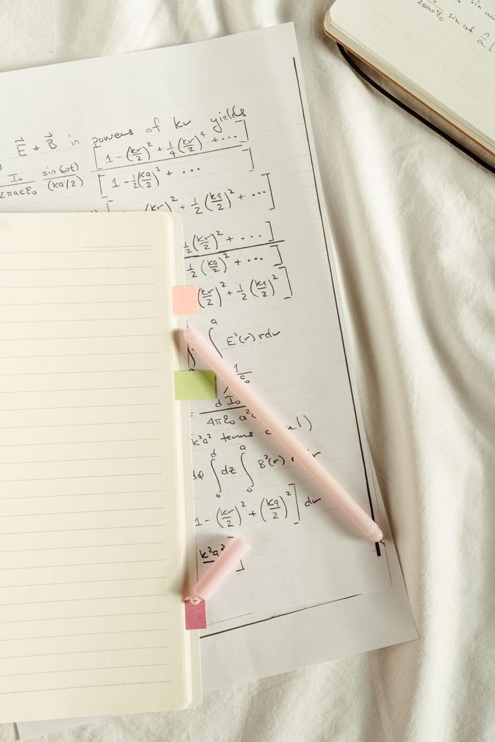 Flat lay of handwritten mathematical formulas and notes with colorful sticky notes and pen.